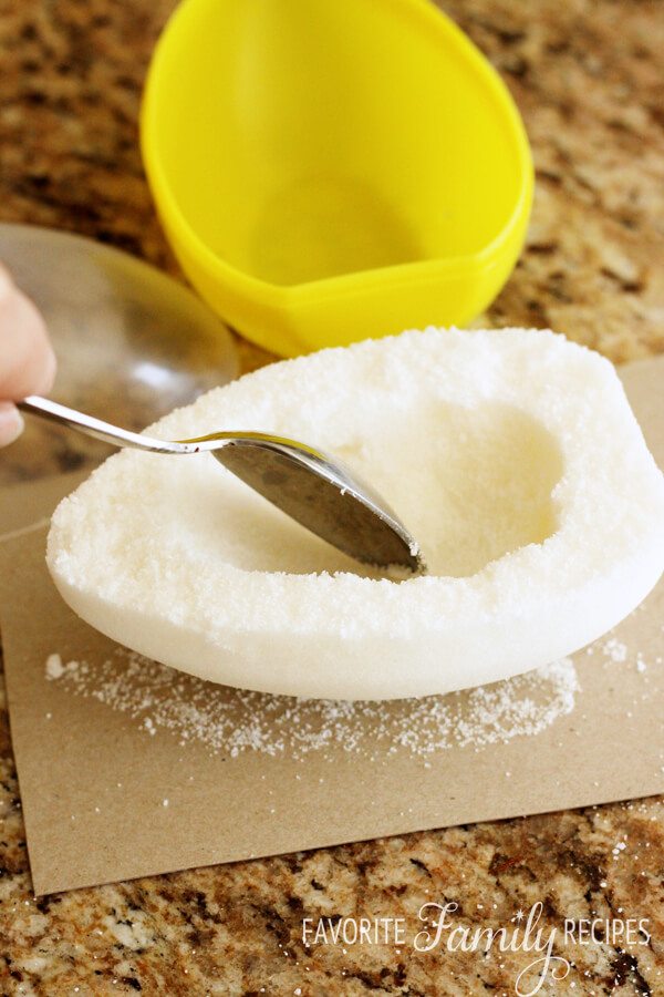Scraping the center of a sugar egg mold with a spoon