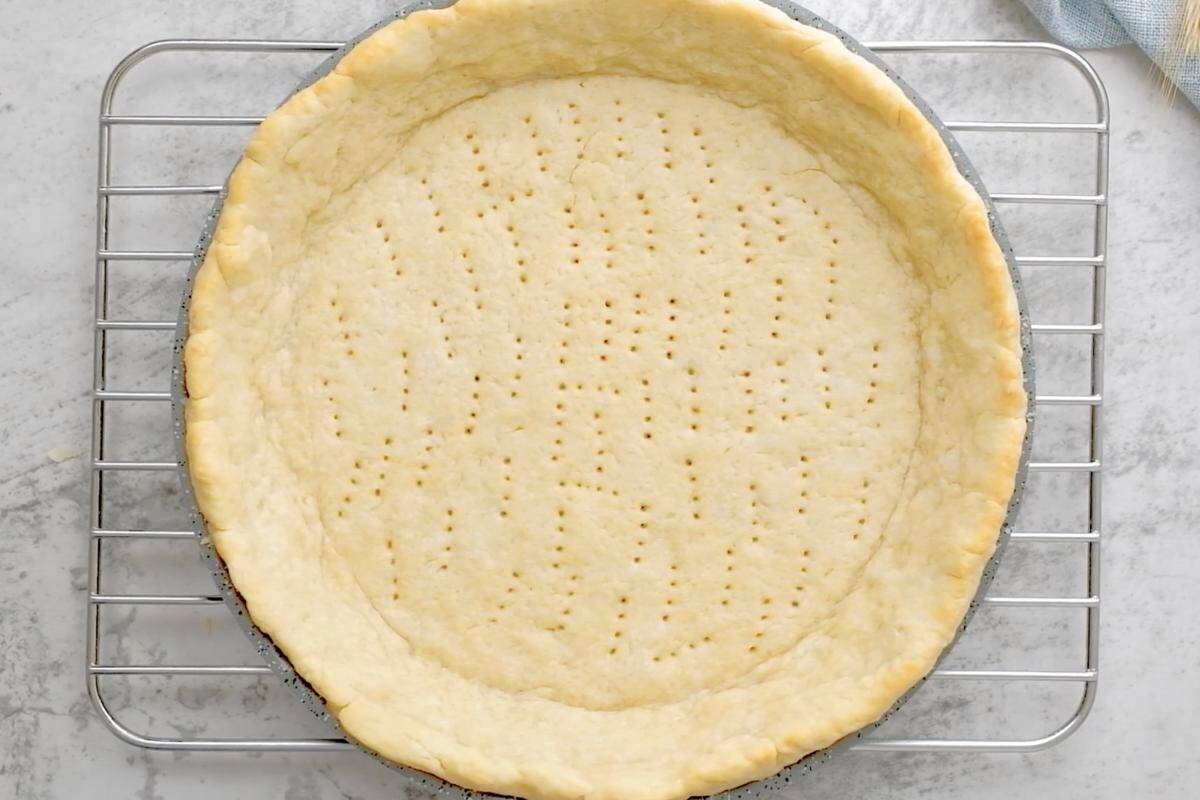 A pre baked pie crust with golden edges on a cooling rack