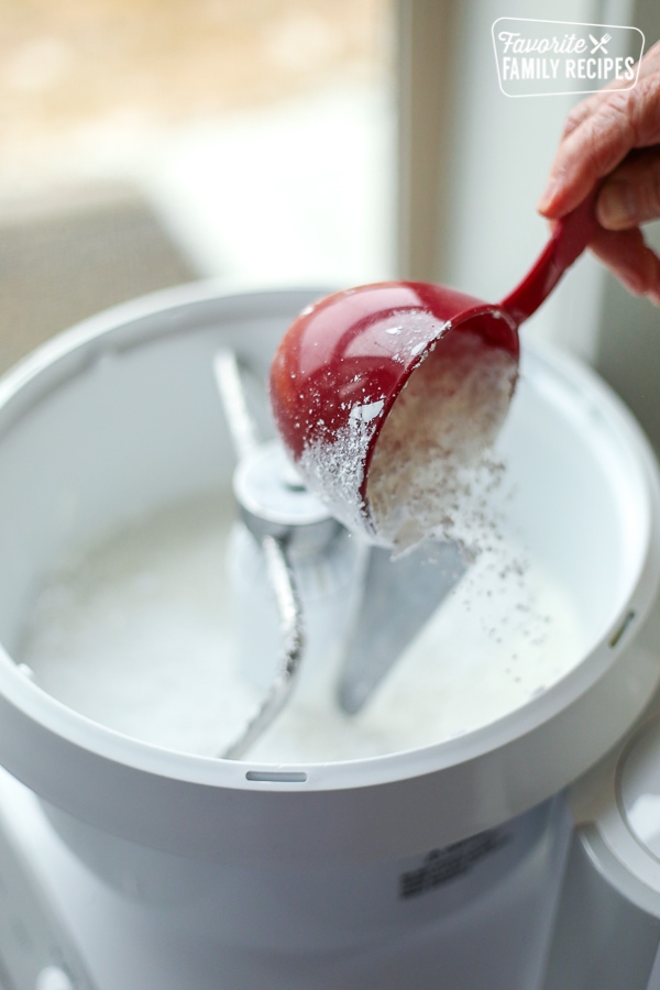 Powdered sugar being poured from a measuring cup into fondant