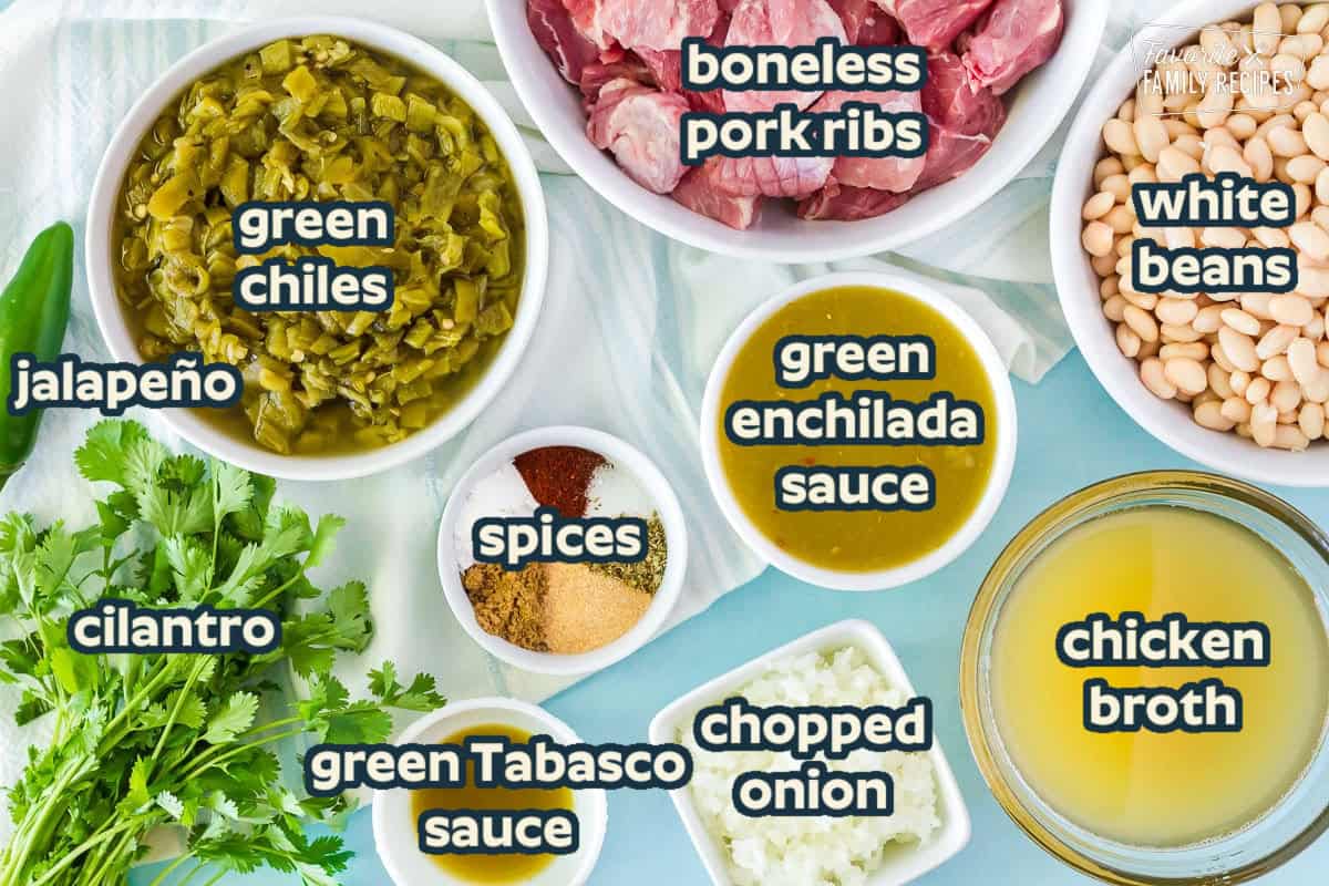 Bowls of raw cubed pork shoulder, white beans, chicken broth, green enchilada sauce, green tobacco sauce, chopped onions, seasonings and green chilies. Fresh jalapeño and cilantro on the side all to make Pork Chili Verde.