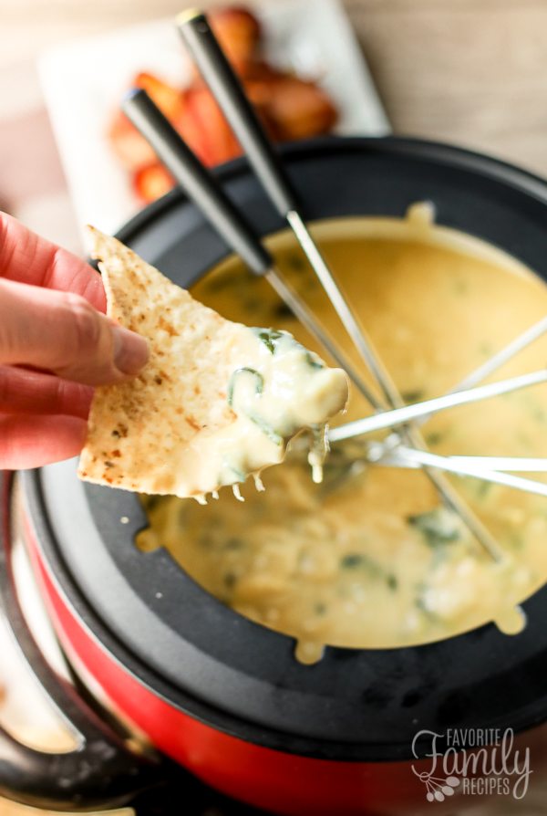 A chip dipped into the Spinach Artichoke Cheese Fondue.