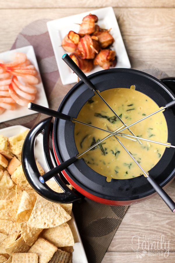 The Melting Pot's Spinach Artichoke Cheese Fondue surrounded by shrimp, meat, and chips.