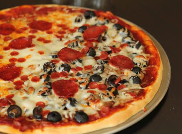 A pizza made with homemade pizza dough that is half cheese half pepperoni and olives