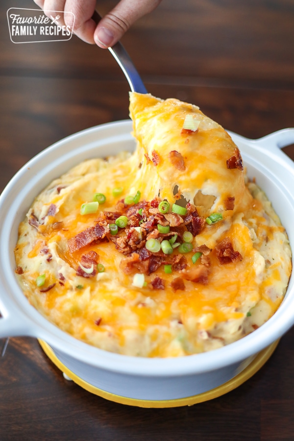 Loaded Mashed Potatoes being spooned out of a baking dish.