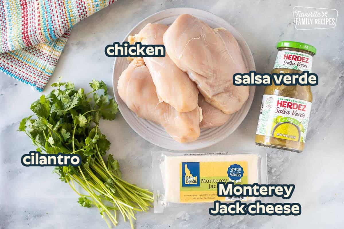 Ingredients to make Slow Cooker Salsa Verde Chicken including chicken breasts, salsa verde, Monterey Jack cheese and cilantro.