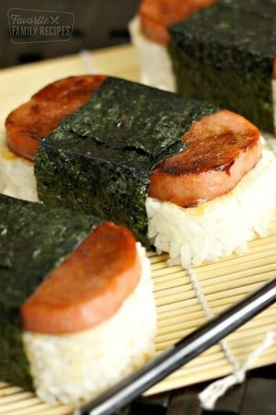 Spam Musubi, rice and spam wrapped in seaweed, on a bamboo sheet.