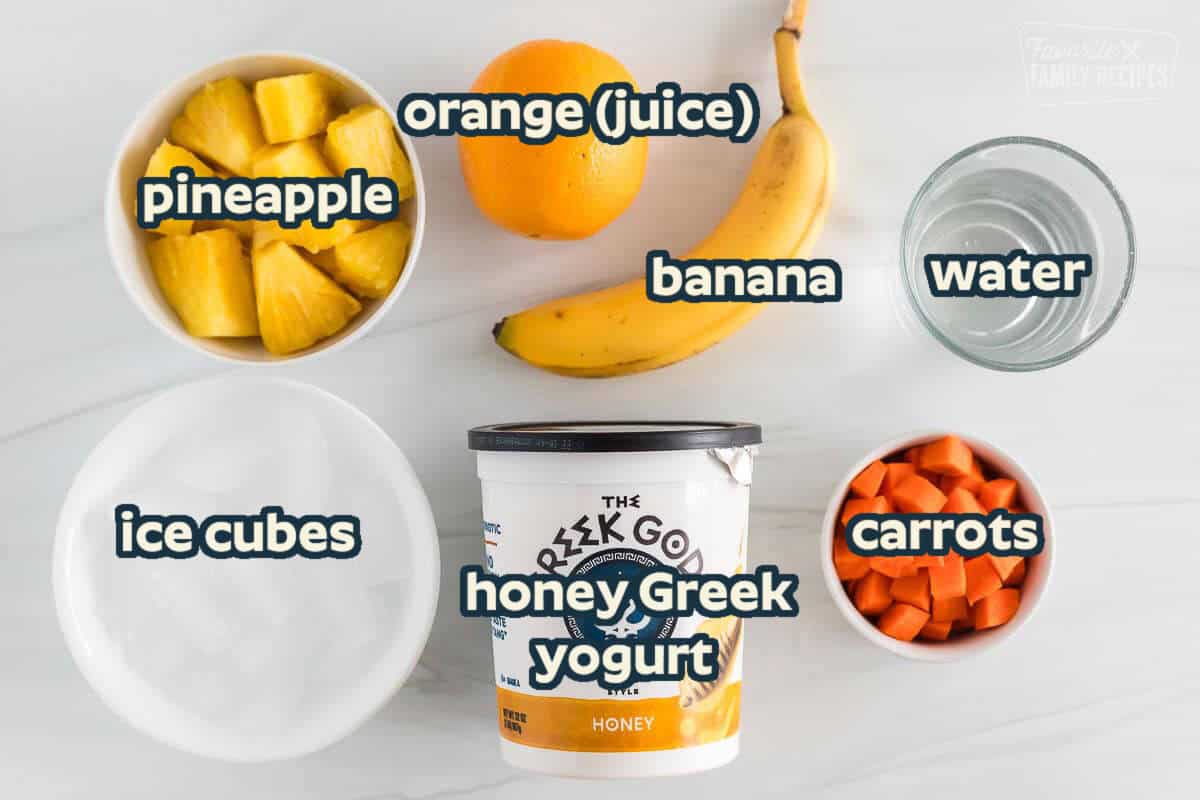 Ingredients for a golden detox smoothie including honey greek yogurt, carrots, pineapple, a banana, orange juice, water and ice