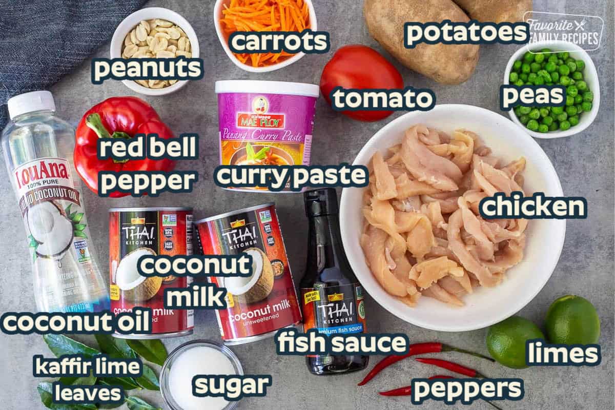 Ingredients to make Chicken Panang Curry including chicken, panang curry paste, peas, potato, tomato, carrot, peanuts, red bell pepper, coconut milk, fish sauce, limes, sugar, Kaffir lime leaves, coconut oil and chilies for garnish.