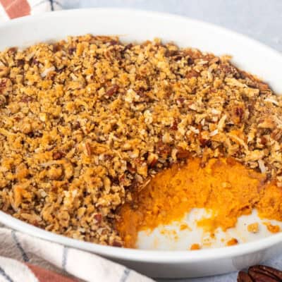 Sweet Potato Casserole with Pecan Topping in a casserole dish with scoop out of it.