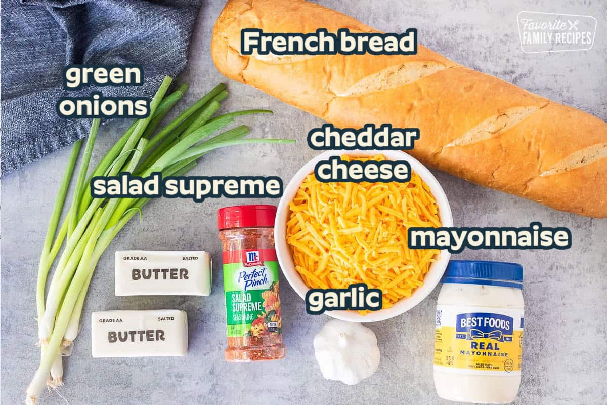 Ingredients to make a garlic bread spread recipe: garlic, cheese, green onions, butter, mayonnaise, and salad supreme