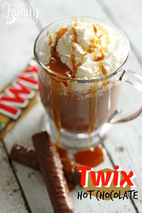 Twix hot chocolate in a glass mug with caramel drizzled overtop.