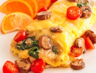 Veggie Omelet on a plate with sliced oranges