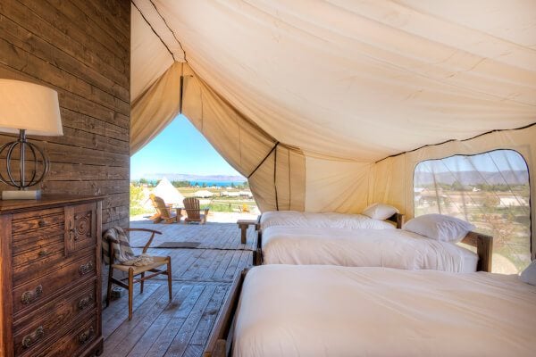 The inside of a tent with three beds and a dresser. 