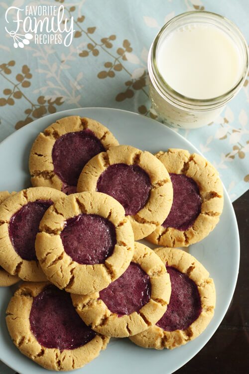 Peanut butter and jelly cookies - a fun spin on traditional peanut butter cookies, and the best way to enjoy that classic peanut butter and jelly combo. Pair these peanut butter and jelly cookies with a tall glass of milk and you'll have a protein-fueled snack filled with irresistible flavor. Peanut Butter and Jelly Cookies on a light blue plate.