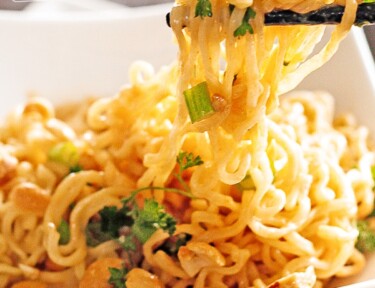 Two minute Thai Peanut Noodles being lifted with chopsticks from a white square bowl