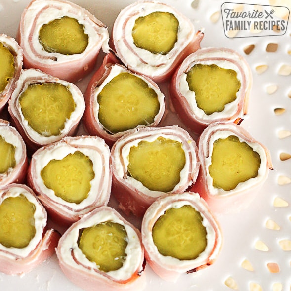 Several Ham and pickle roll ups from above on a white plate.