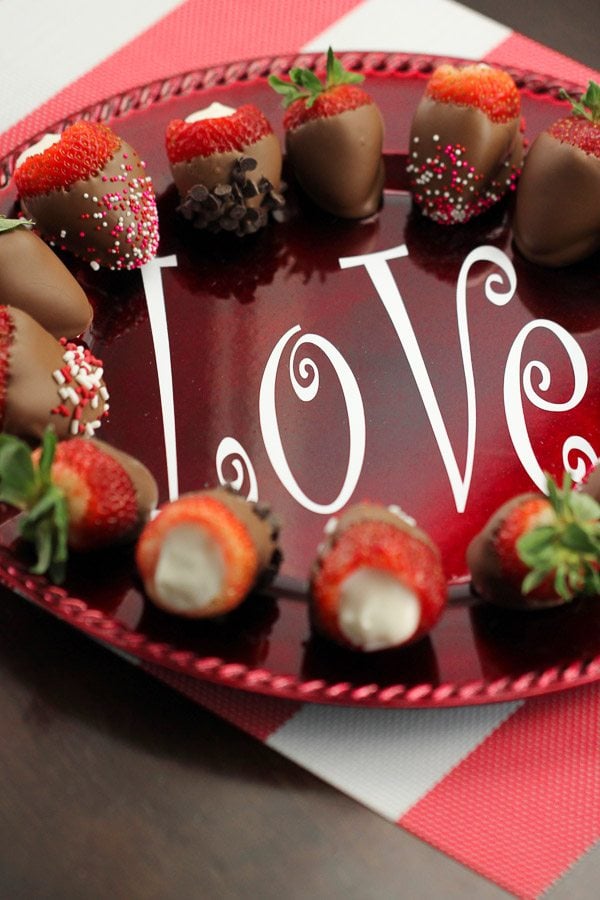 Cheesecake Stuffed Chocolate Dipped Strawberries in a circle on a plate that says love.