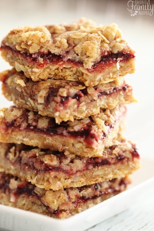 Raspberry Oatmeal Crumb Bars are a sweet, buttery, fruity bar cookie with a nutty, crumbly crust. The perfect bar cookie for any occasion! A stack of five Raspberry Oatmeal Bars on a square white plate