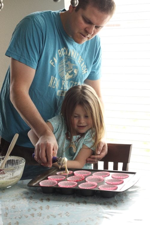 Jared helping his daughter fill the cupcake pan with cupcake batter. 