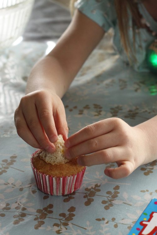 Hands placing the top of a cupcake back on the hollowed out cupcake