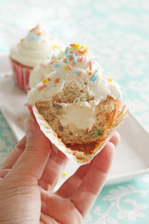 A cupcake cut in half to see the middle of the whip cream. 