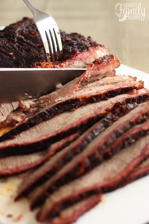 Smoked brisket being sliced with a fork and knife.