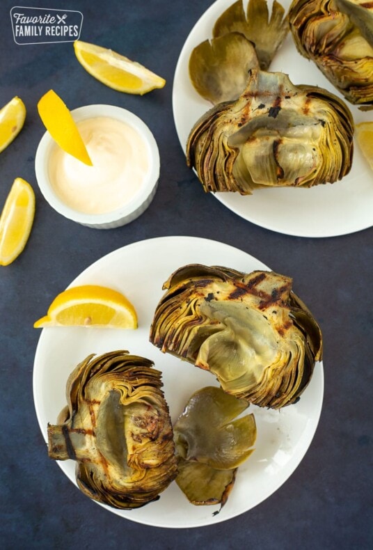Grilled Artichokes on 2 plates with lemon dip