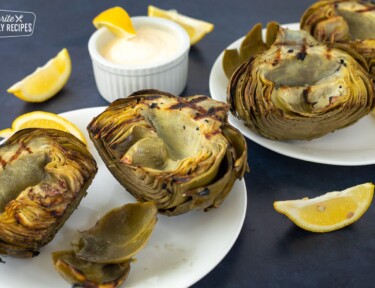 Grilled Artichokes on 2 plates with lemon dip