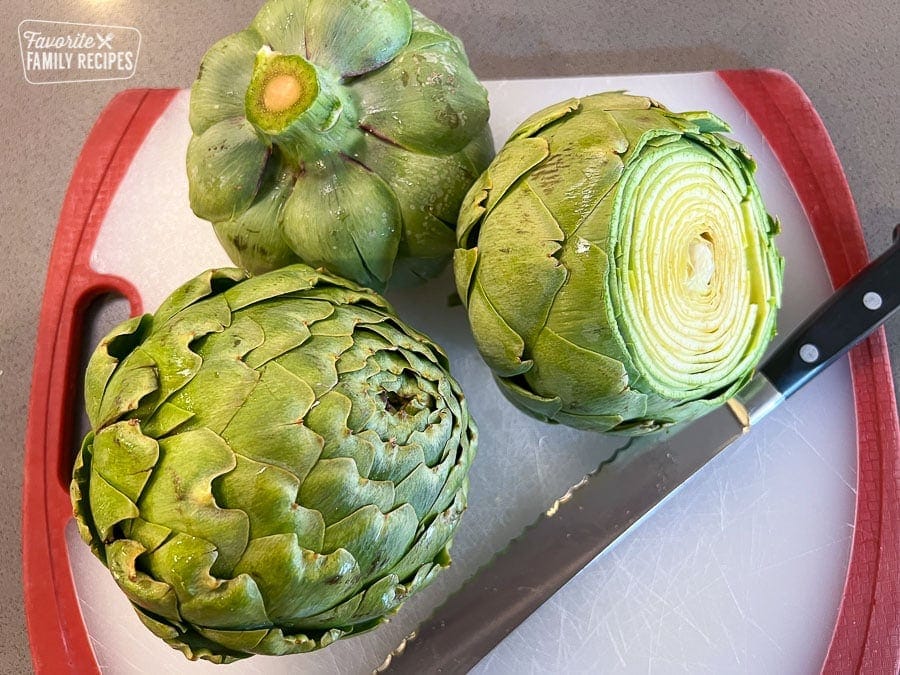 Cutting artichokes on a white cutting board.