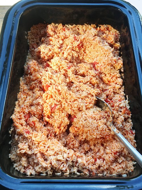 Seasoned rice in a large tray with a serving spoon.