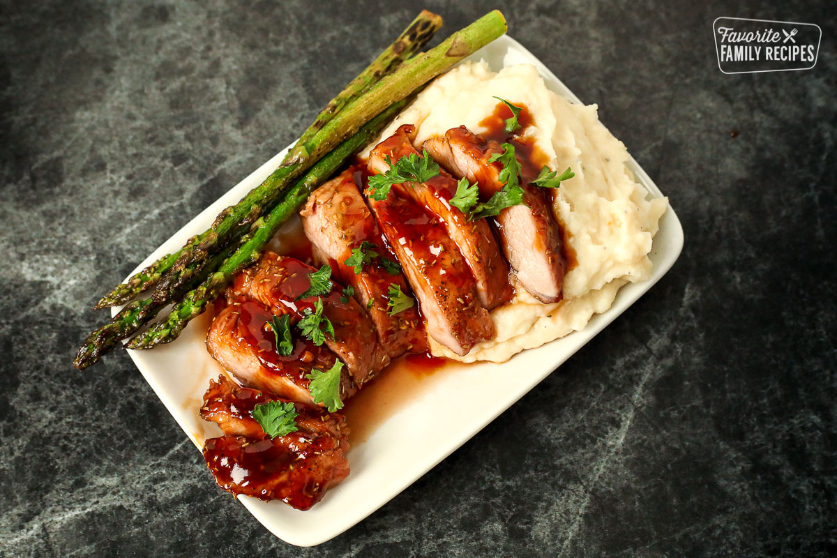 Plate with mashed potatoes, asparagus, and sliced pork tenderloin