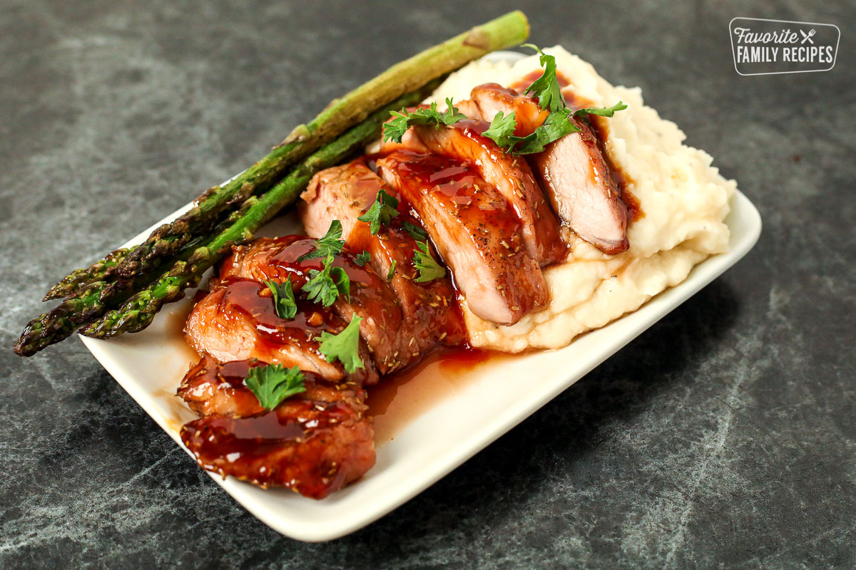 Plate with mashed potatoes, asparagus, and sliced pork tenderloin