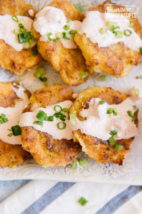 Close up image of cheesy potato cakes drizzled with sauce and sprinkled with green onions