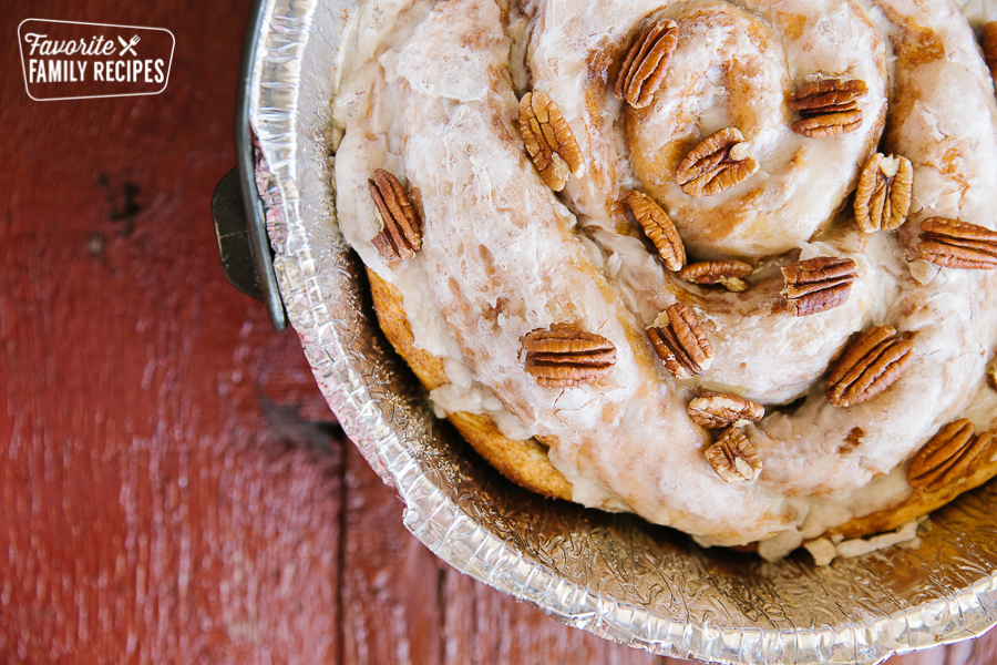 A Dutch Oven Cinnamon Roll with a glaze and pecans on top.