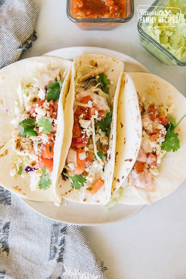 Grilled Mahi Mahi Fish Tacos on a plate with condiments on the side