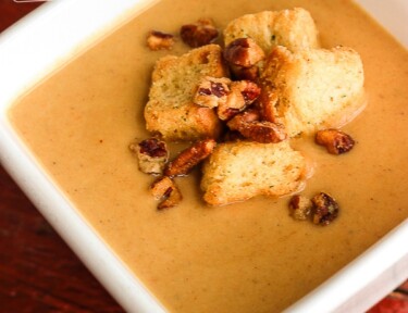Creamy Butternut Squash Soup topped with croutons in a white square bowl.