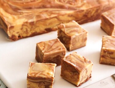 Chocolate Peanut Butter Fudge Swirl slab with cut up pieces on a cutting board