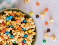 Peanut Butter Popcorn in a bowl surrounded by a blue gingham napkin