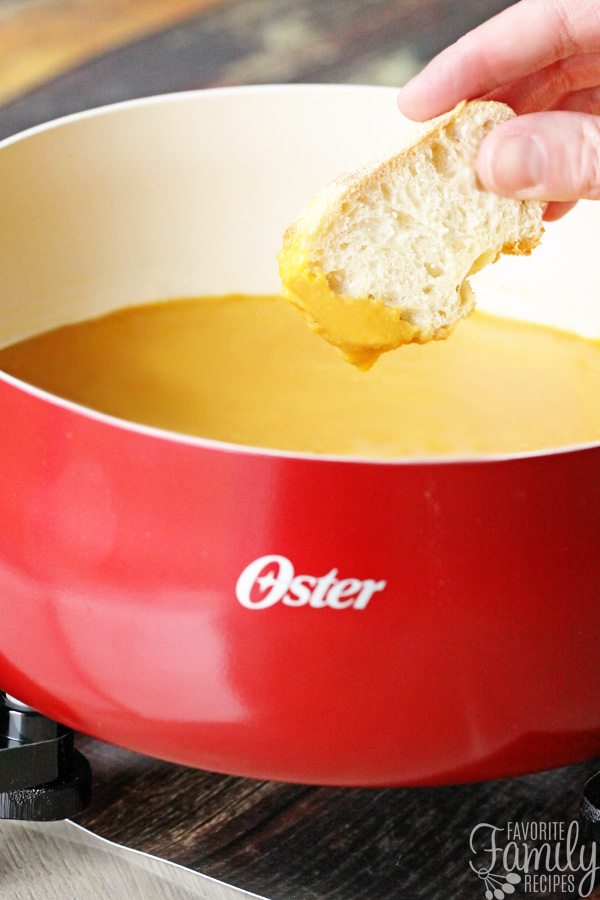 Bread dipped in cheddar cheese fondue in a fondue pot