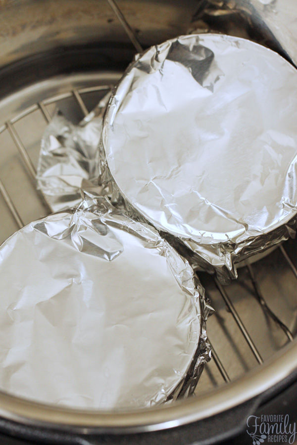 Two ramekins filled with lemon custard and covered with tin foil sitting inside an Instant Pot