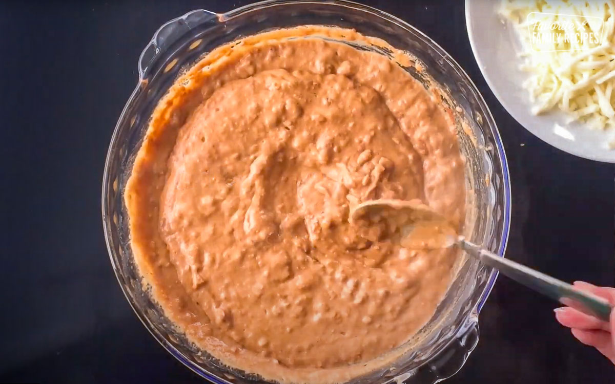 Stirring refried beans in a glass pan