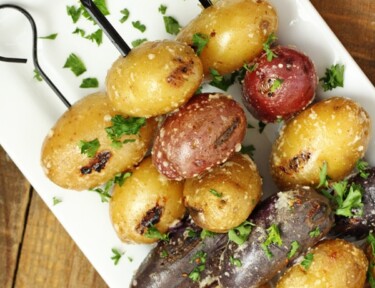 Parmesan garlic grilled potatoes on a skewer on a white plate.