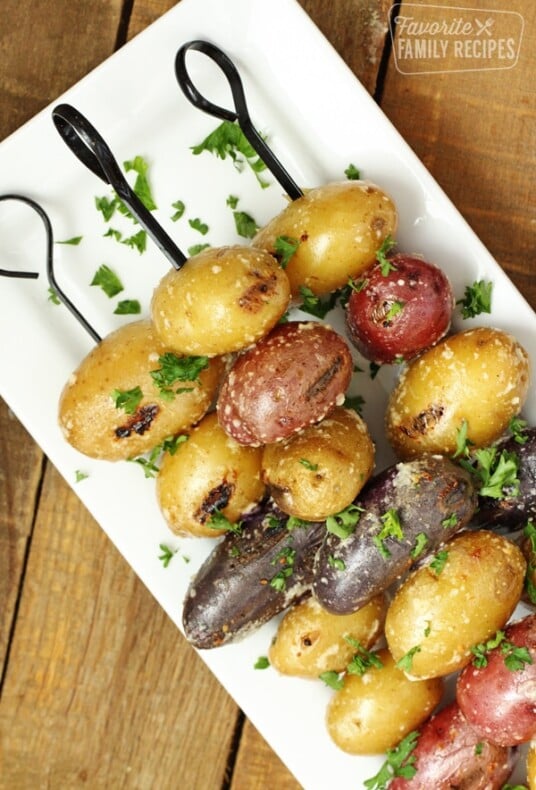 Parmesan garlic grilled potatoes on a skewer on a white plate.