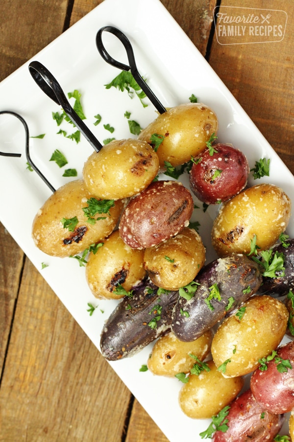 Skewers filled with parmesan potatoes on a white platter. 