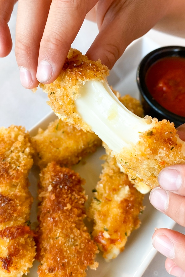 Mozzarella stick being pulled to show cheese