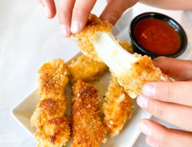 Mozzarella stick being pulled apart to show cheese