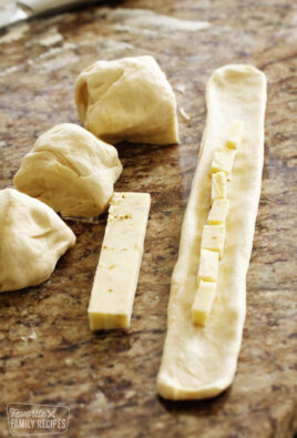 Dough flattened out in a long strip with cheese placed down the center.