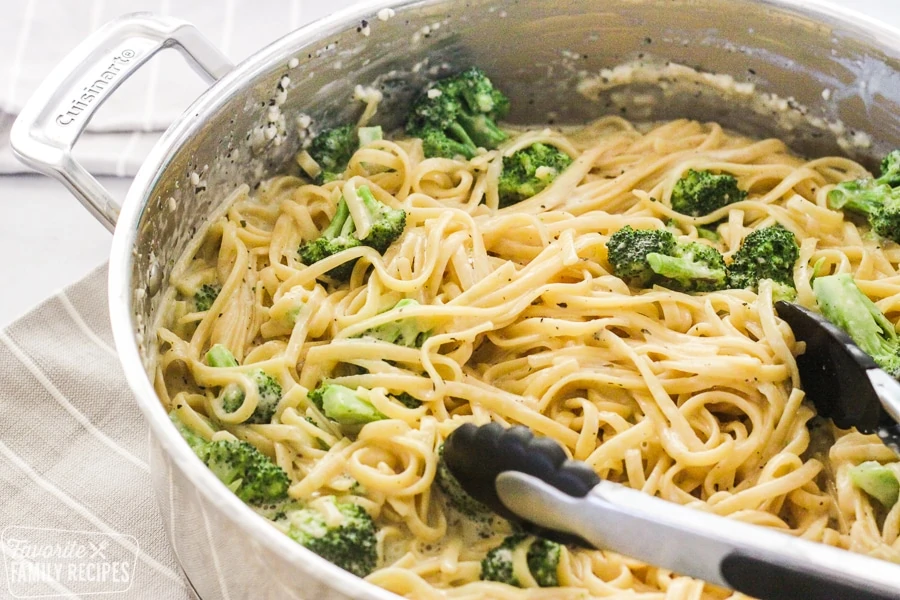 Una pentola di spaghetti cremosi in una pentola con broccoli