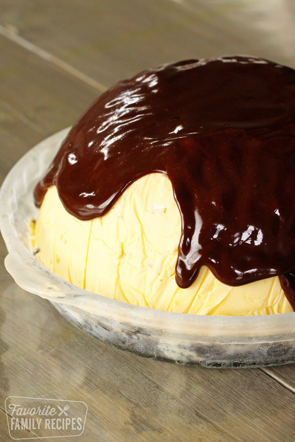 A large "dome" of ice cream in a pie pan over an Oreo crust with chocolate fudge topping spread over the top