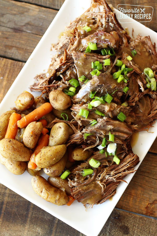 Overhead shot of Instant Pot Sunday Beef Roast shredded on a serving plate with potatoes and carrots
